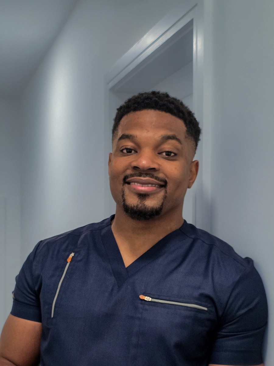 Israel Nwachineke in scrubs, holding a tablet